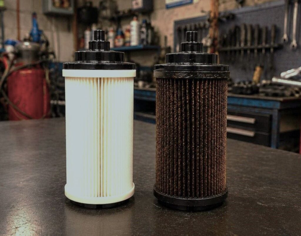 Comparación visual entre un filtro de combustible diésel nuevo y limpio al lado de un filtro usado, negro y obstruido por sedimentos de gasoil.